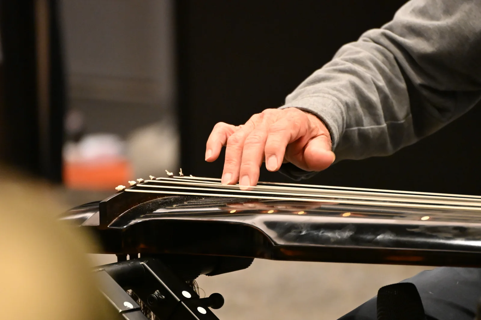 A close view of Fang Jinlong’s hand touching the strings of a guqin