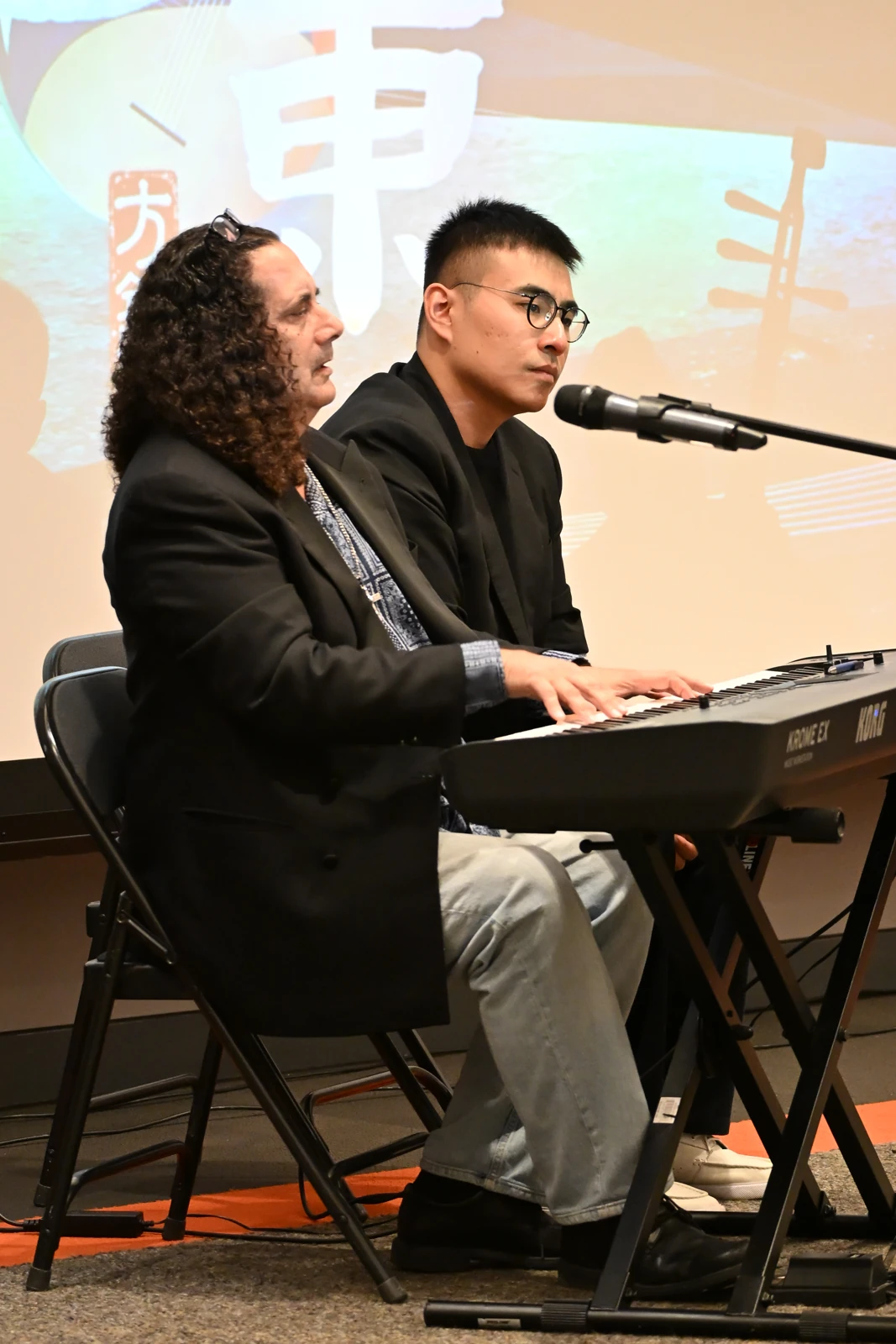Vince di Mura at the keyboard with a fellow participant listening beside him