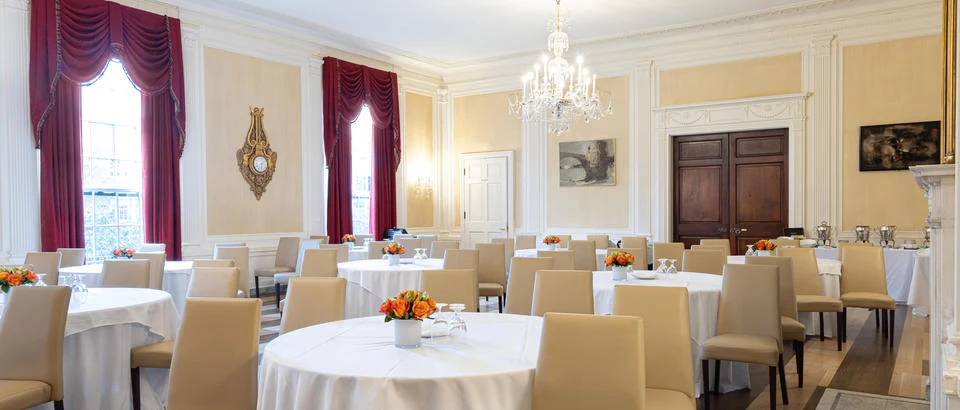 Loeb House ballroom with tall windows, chandeliers and red drapery